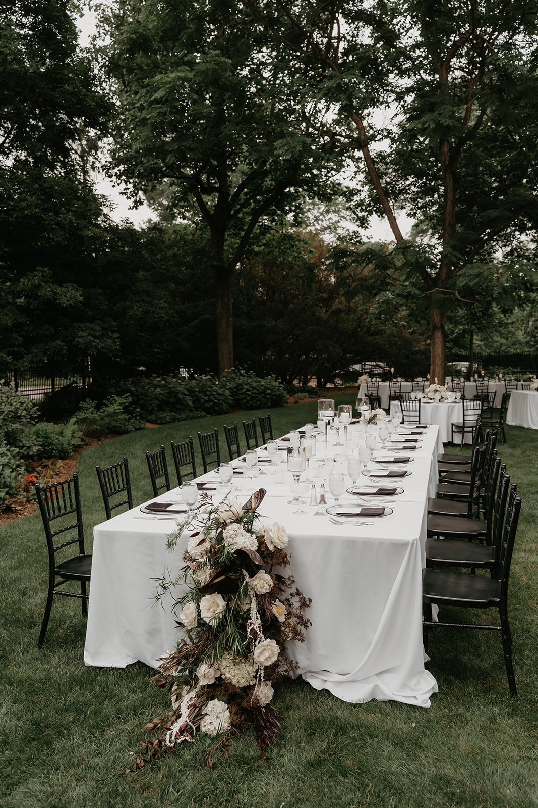 Long Tuscan table with florals cascading off the end and lights in the trees overhead