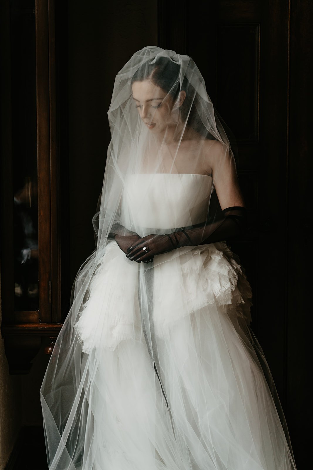 Bride by a window with her Vera Wang veil over her face