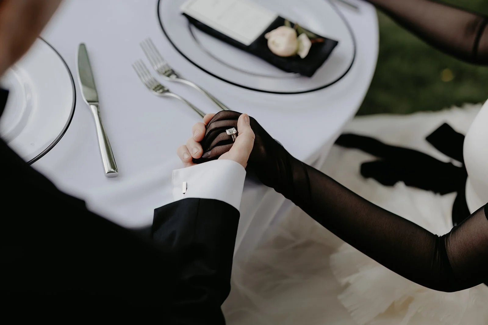 Groom holds bride's hand at sweetheart table