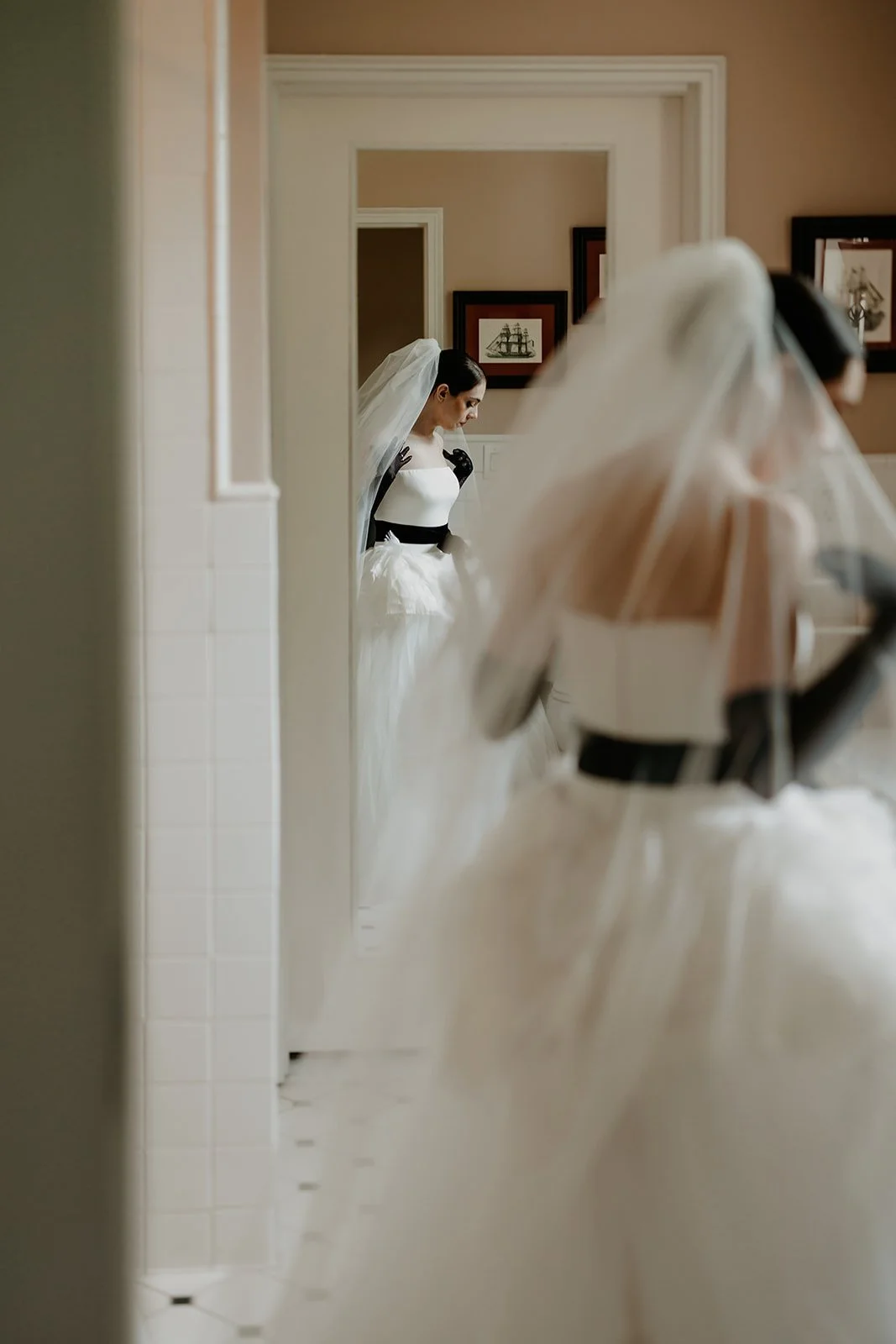 Bride adjusts her veil in a bathroom mirror