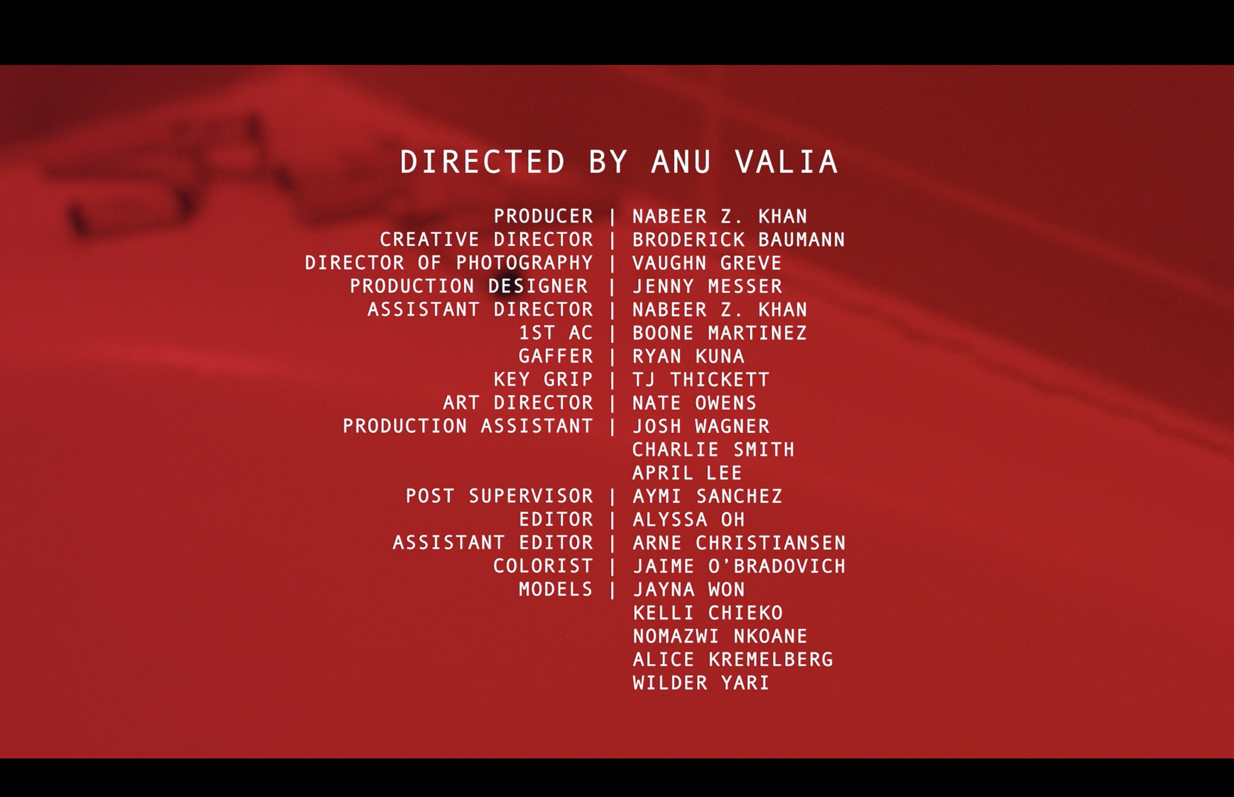 Film or video credits with names and roles listed over a red background.