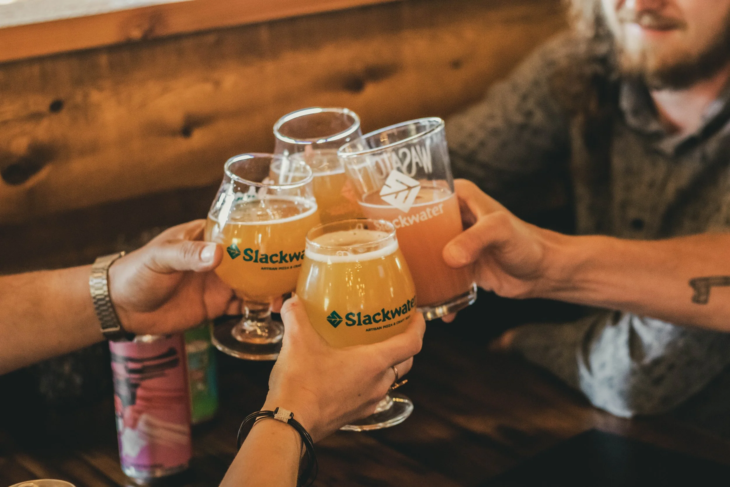 Four people clinking glasses of beer in a toast at a bar or restaurant.
