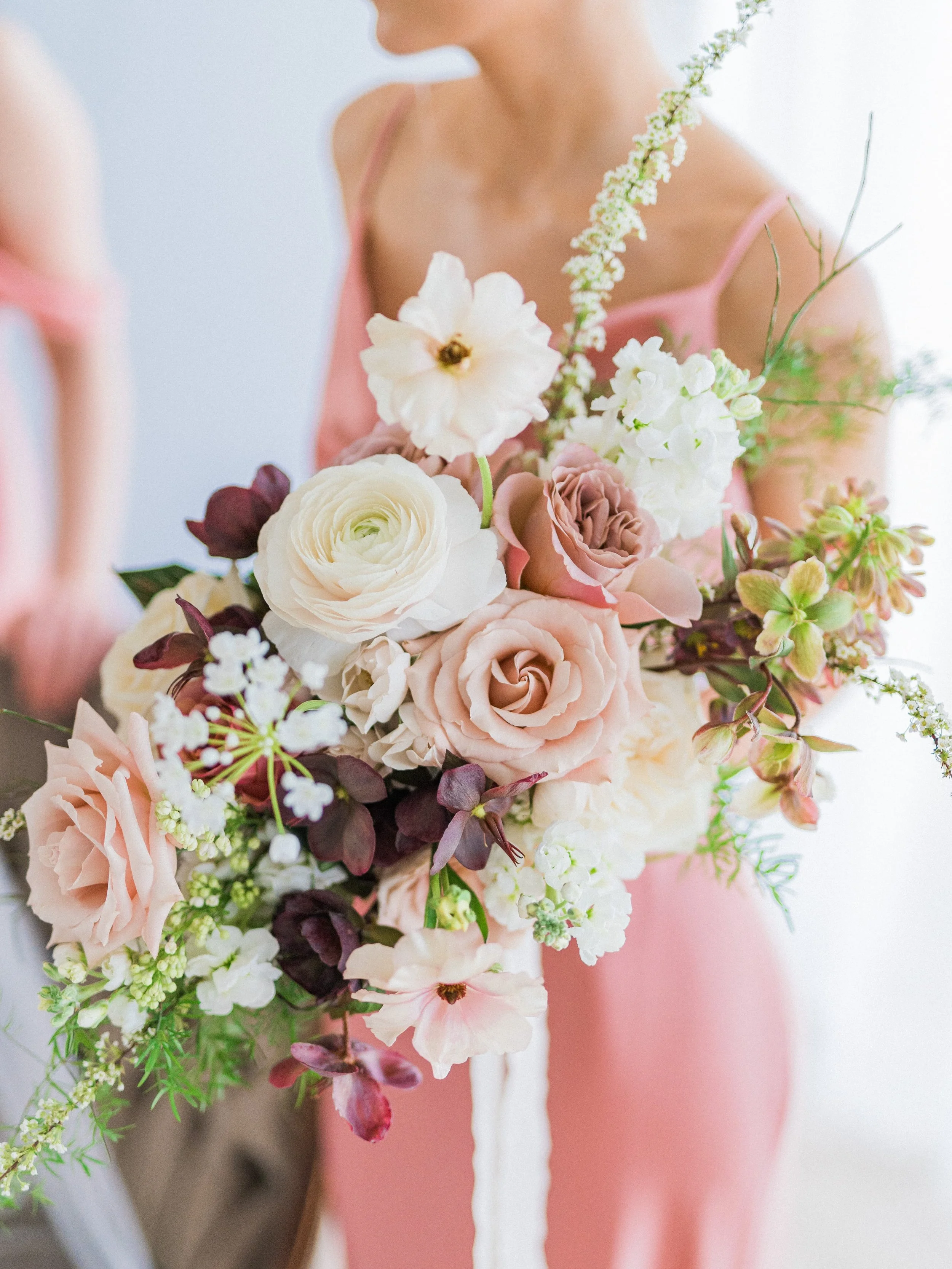 A bridesmaid wearing a pink dress holding a large bouquet of light pink and white flowers from Twig & Bloom Victoria.