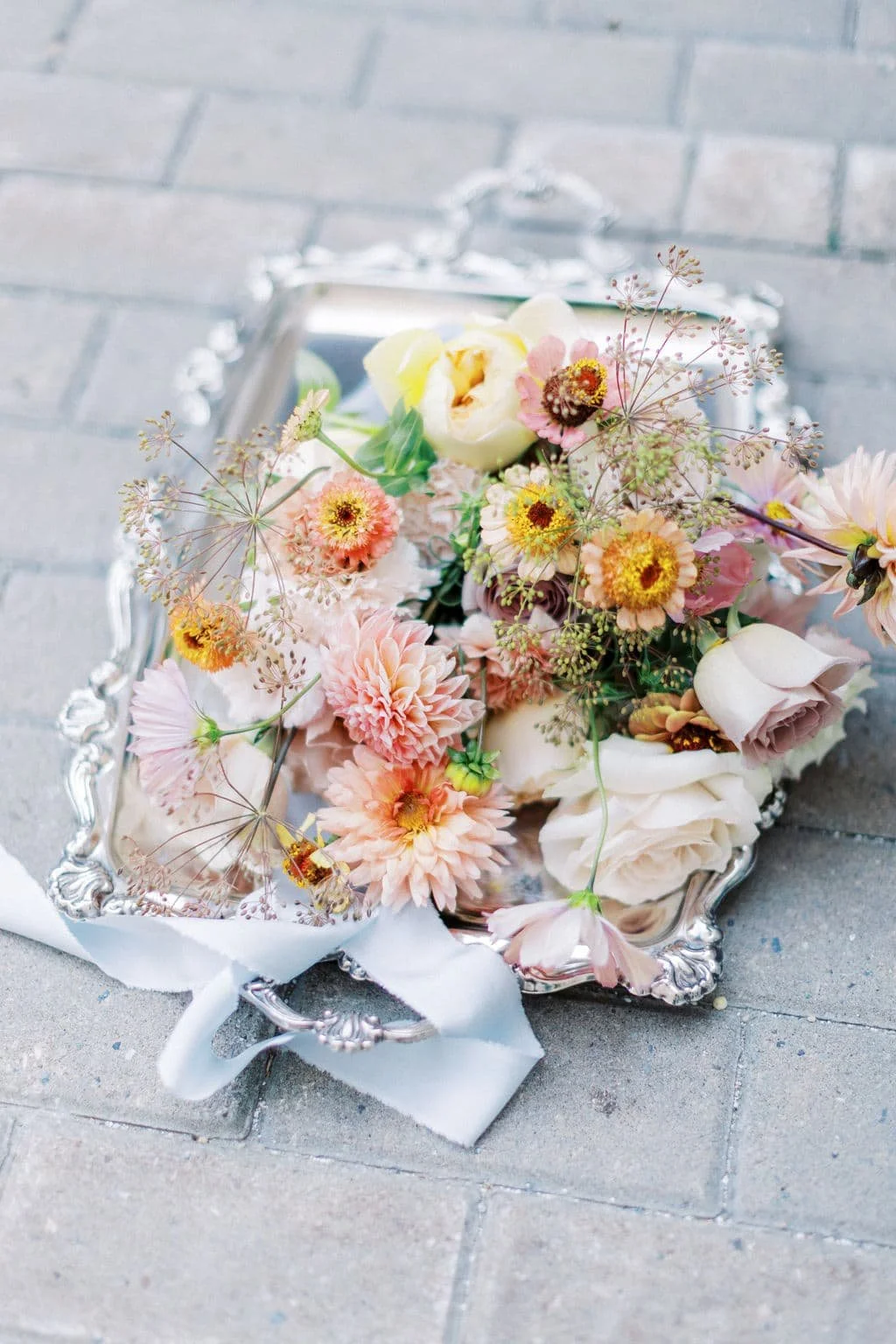 A fall bouquet on a silver platter designed with peach, orange, and pink dahlias and roses. Florals from Twig & Bloom in Victoria, BC.