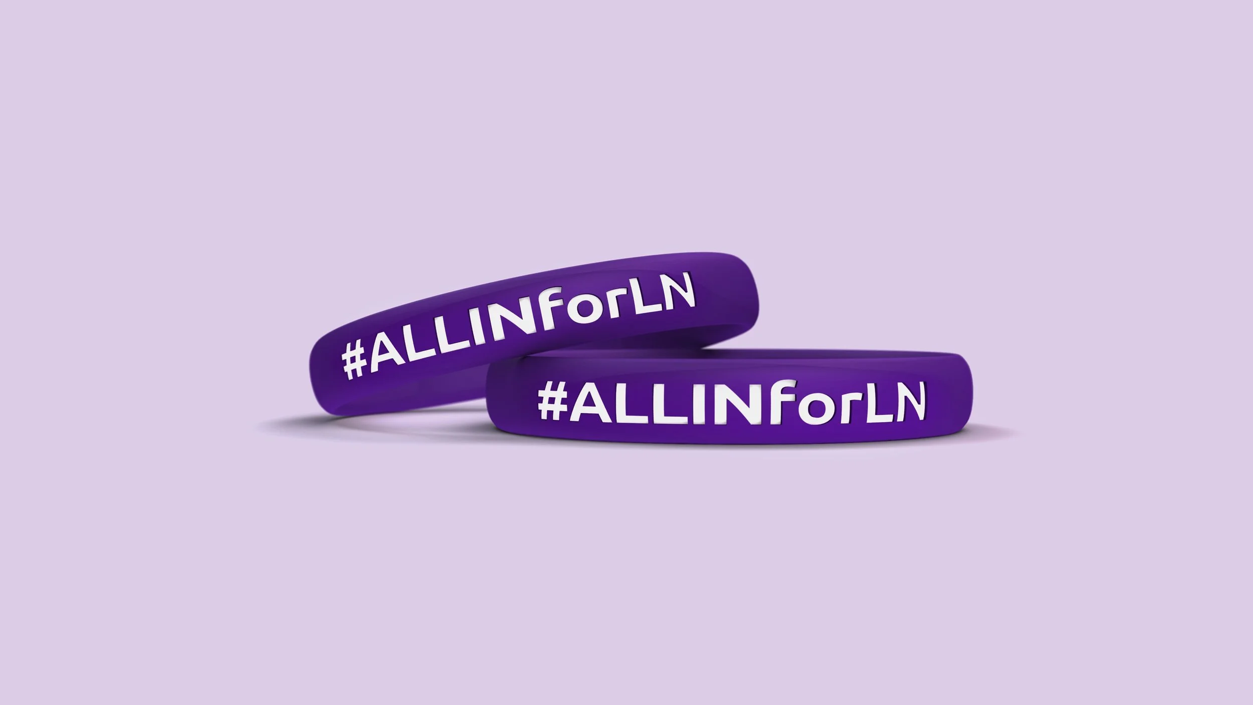 Two purple silicone wristbands with the hashtag '#ALLInForLN' written in white, placed against a light lavender background.