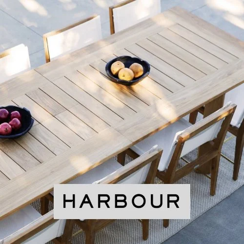 Outdoor wooden dining table with fruit bowls and white chairs