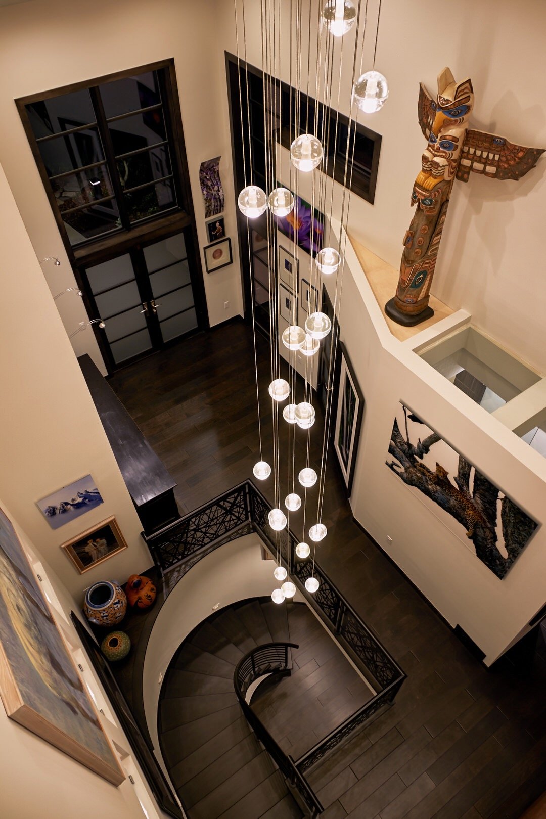 Curved stairway with floating glass globe light, modern entryway remodel