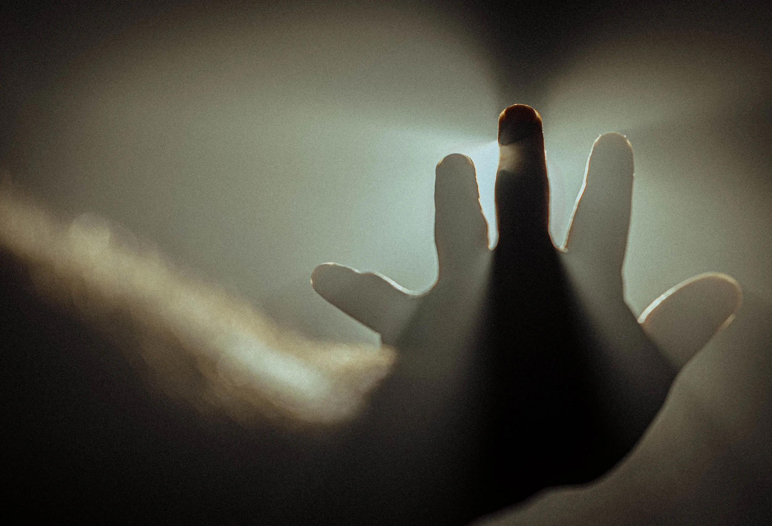 Une main avec le doigt levé, avec une lumière derrière pour créer une silhouette.