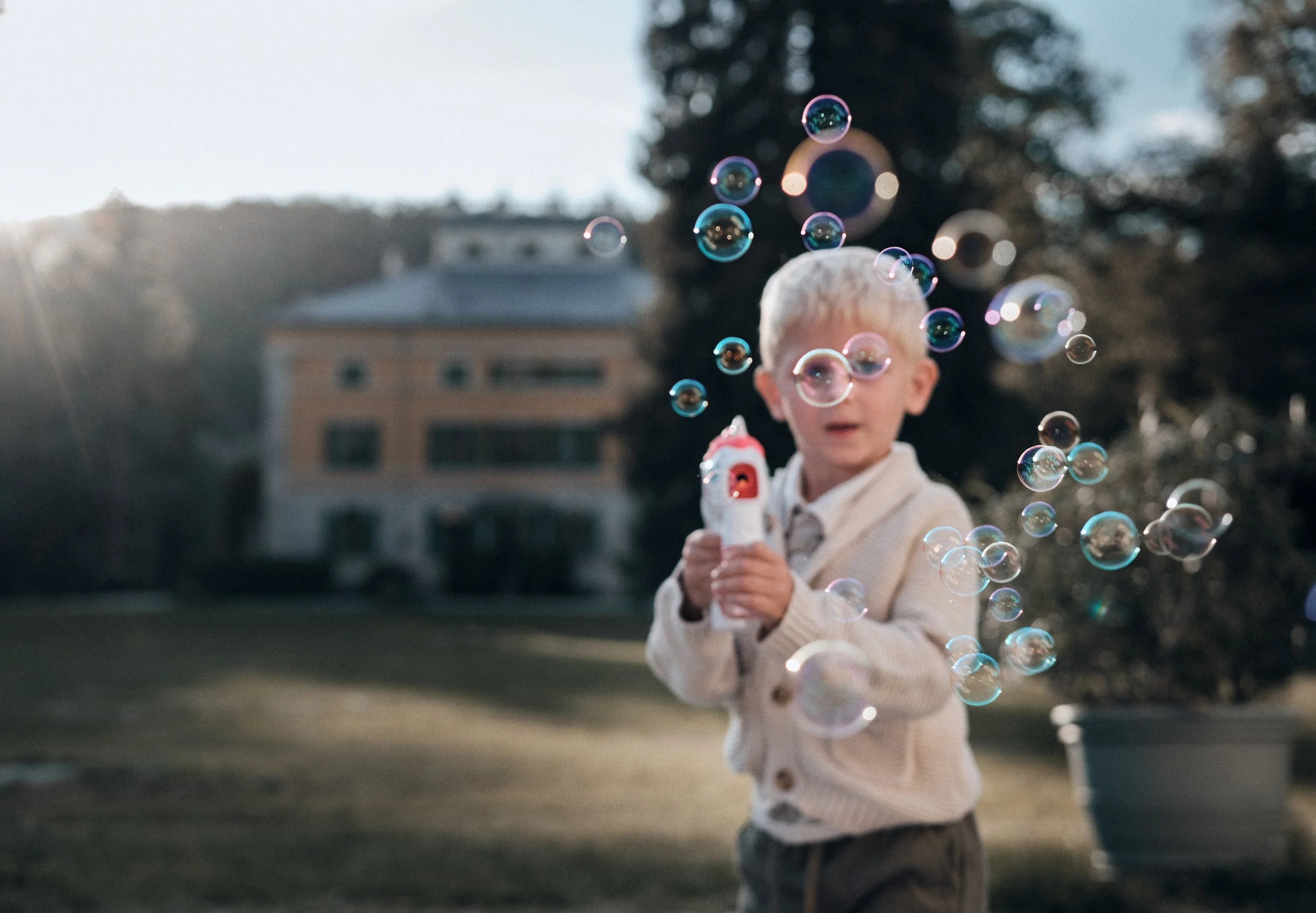Un enfant joue avec un pistolet à bulles devant le Château de Syam du soleil pendant un mariage.
