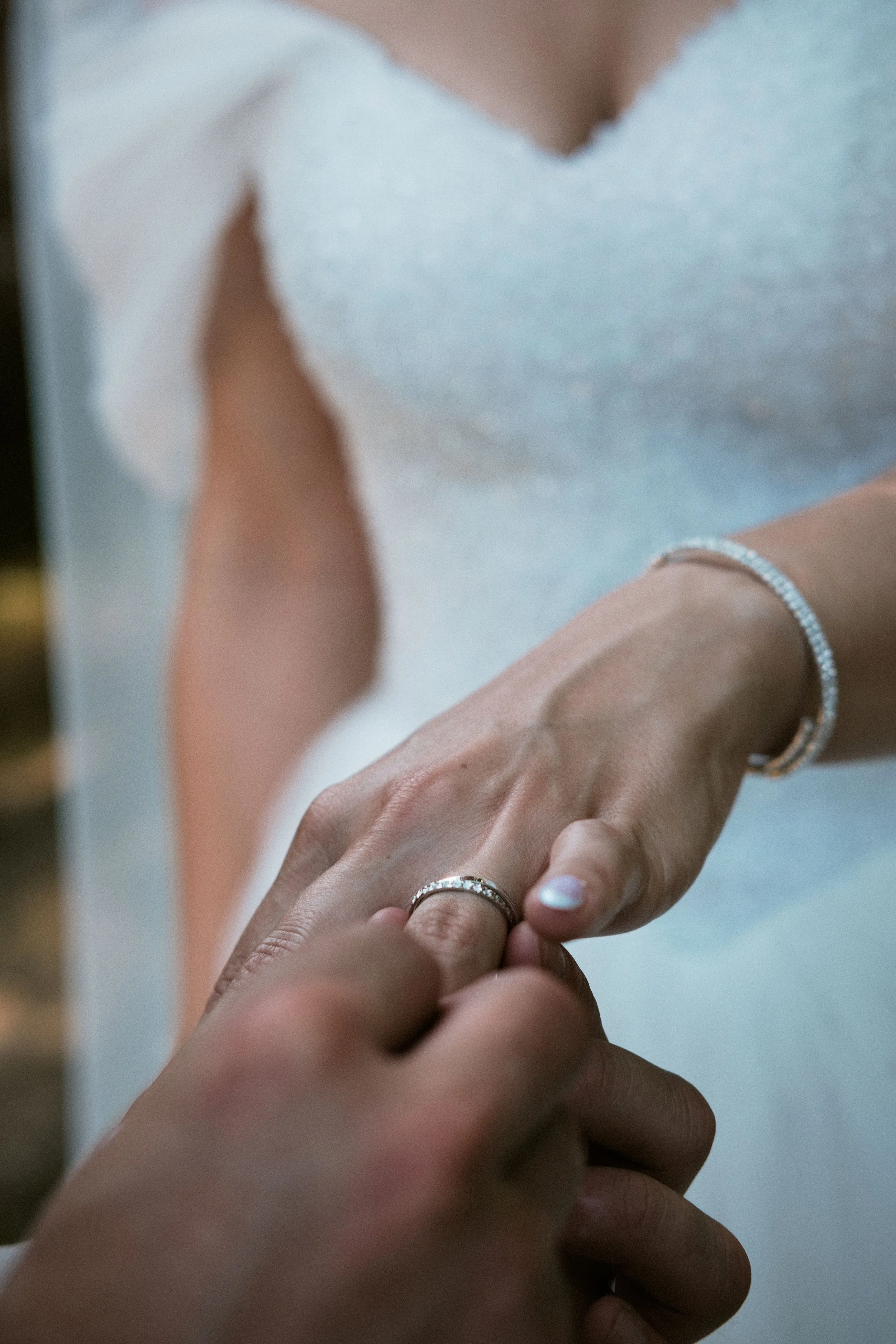 Une personne qui met une bague à une autre personne, un gros plan sur les mains et les bijoux Lors d'un mariage au domaine du Bersaillin dans le Jura