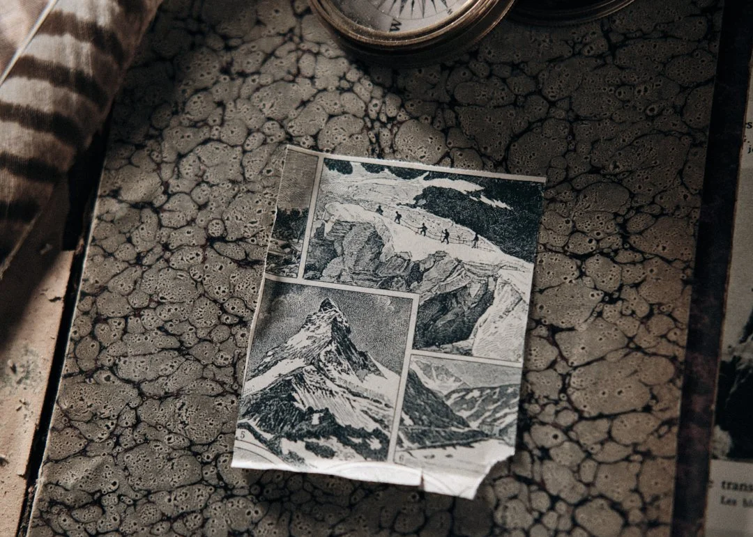 Brochure avec des illustrations de montagnes, dont le Mont Cervin, sur une table en pierre.