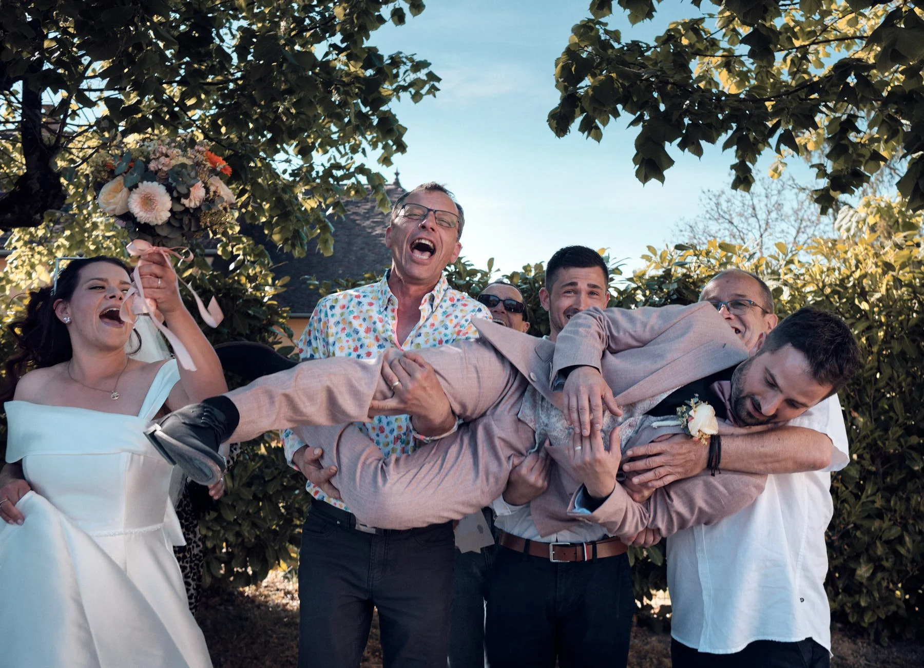 Photo de groupe mariage, les invités portent le marié tout est désordonné