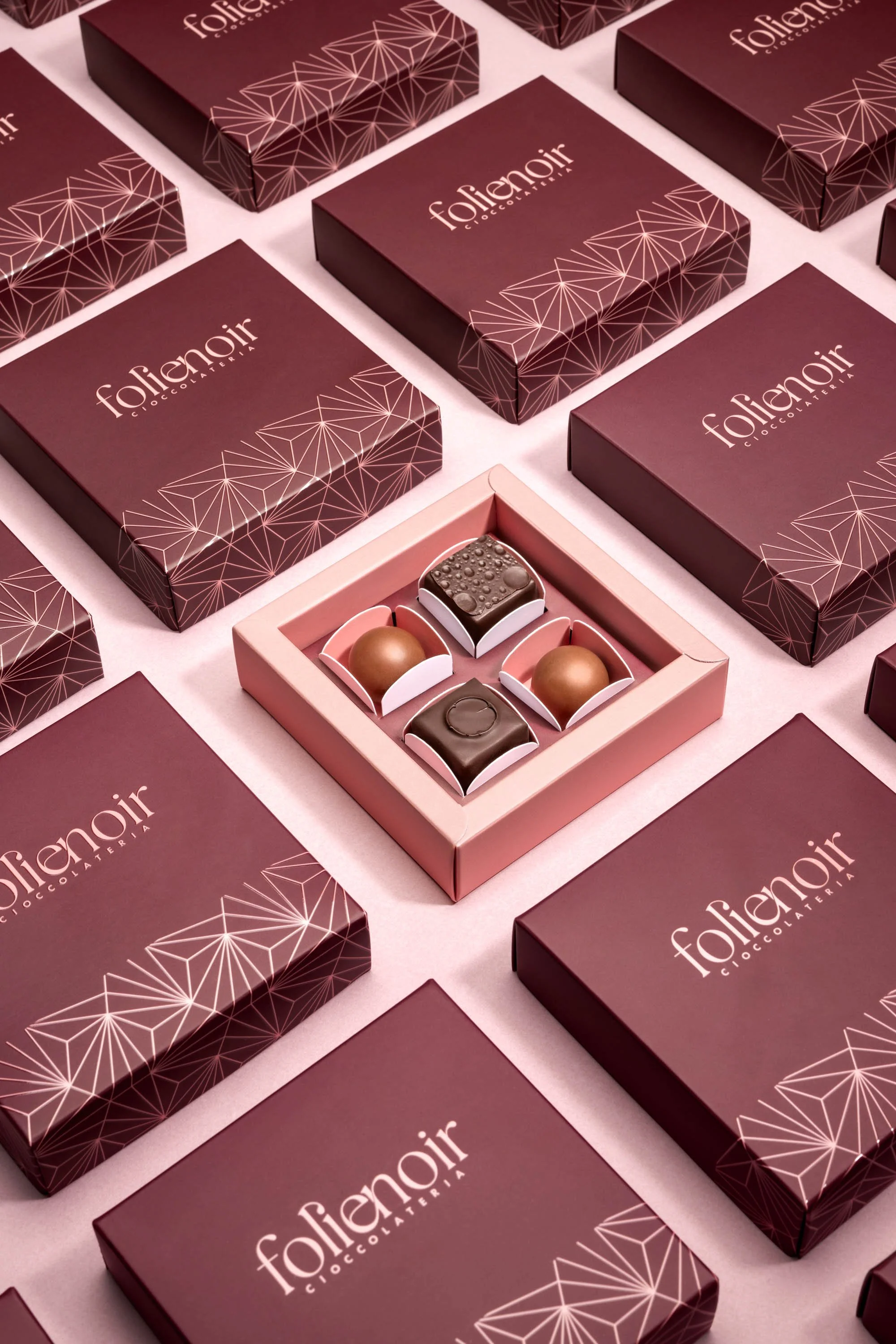 Product photography for Folienoir: chocolates with pink and burgundy packaging.