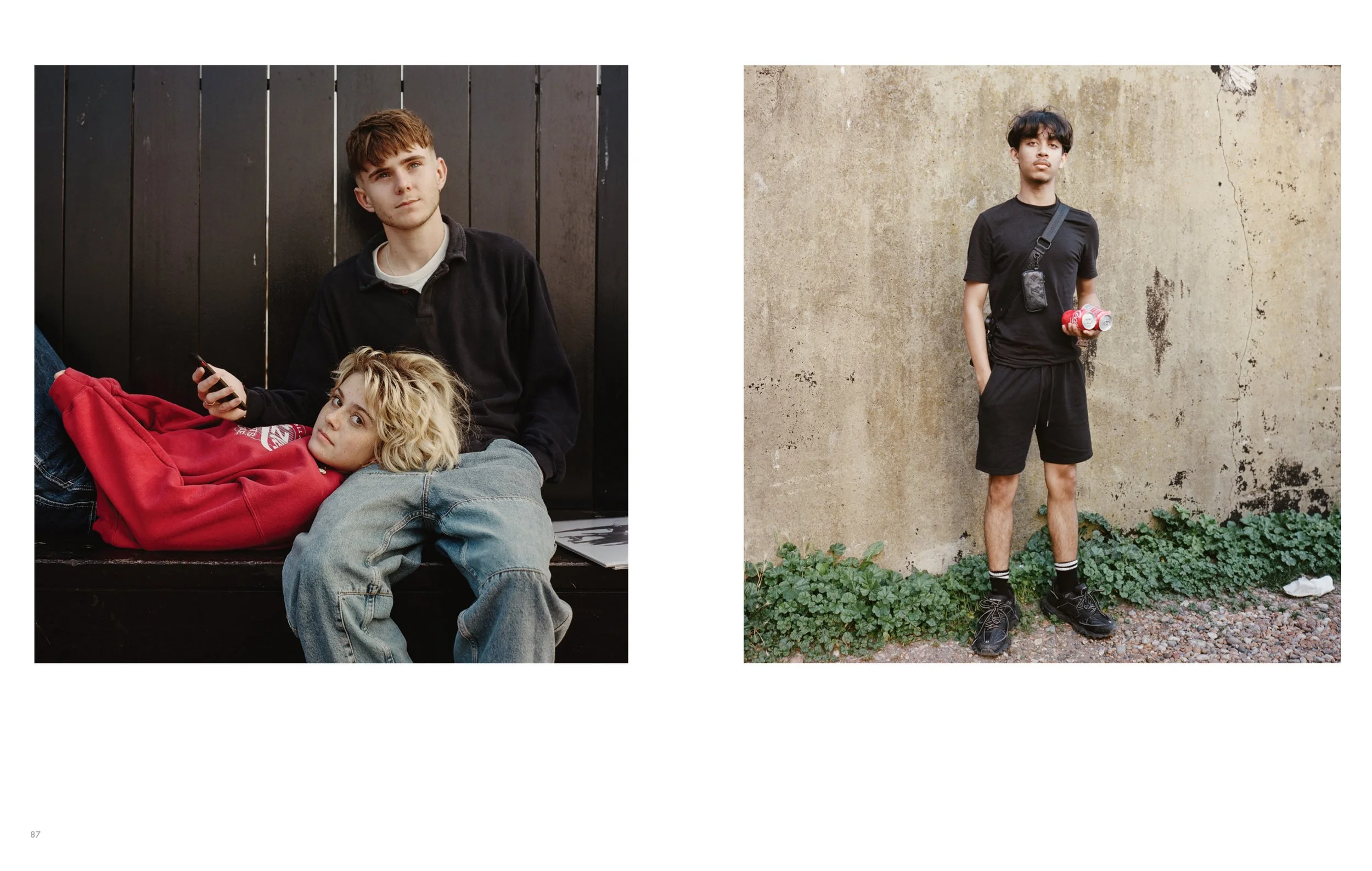 Two young men and a young woman pose outdoors. One man is standing against a textured wall holding soda cans, another man is standing behind the woman with her lying on his lap, and she is resting on her side, looking at the camera. The woman has blo