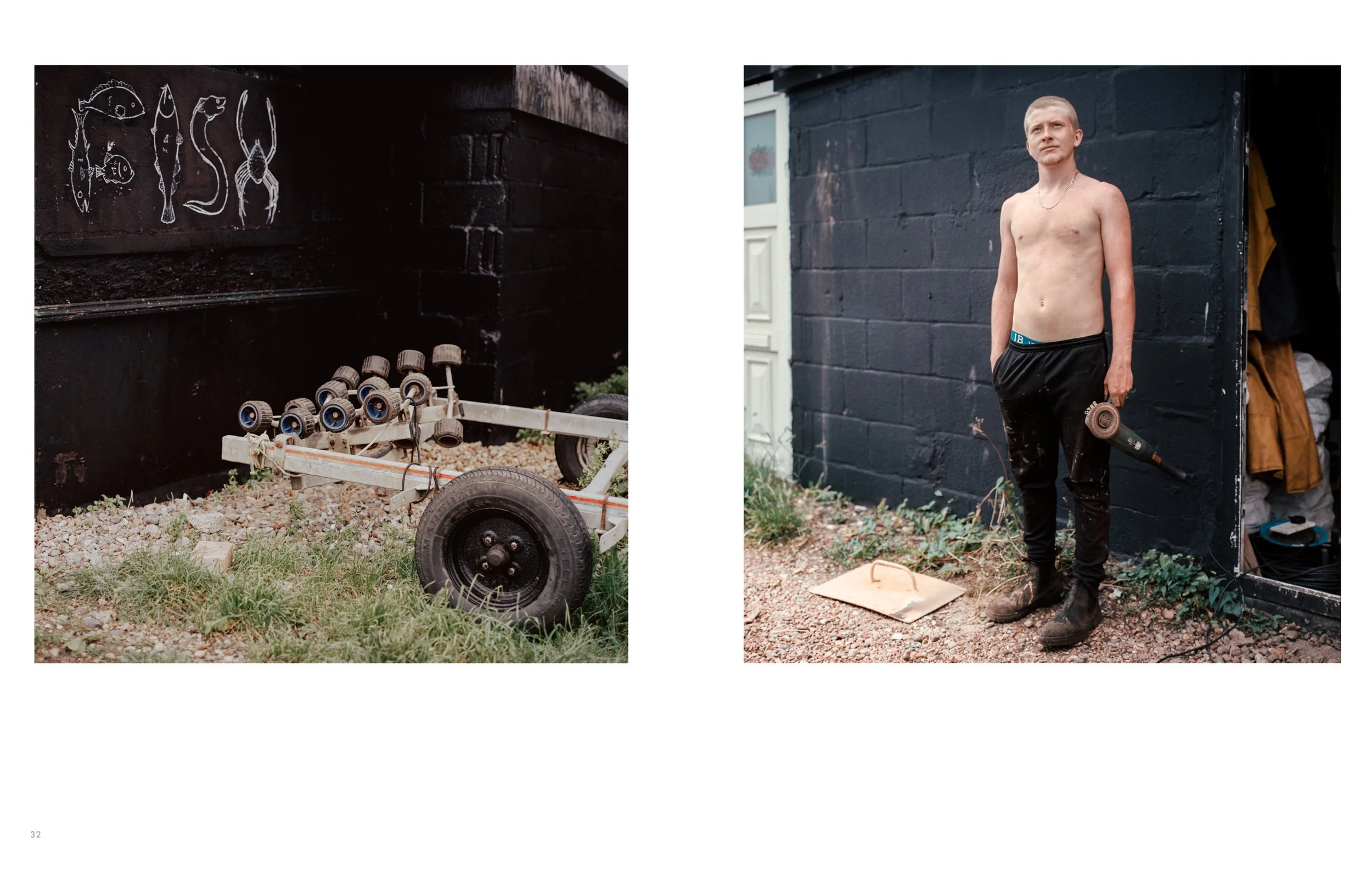 A person standing shirtless outdoors, holding a power drill, in front of a black-painted brick wall.