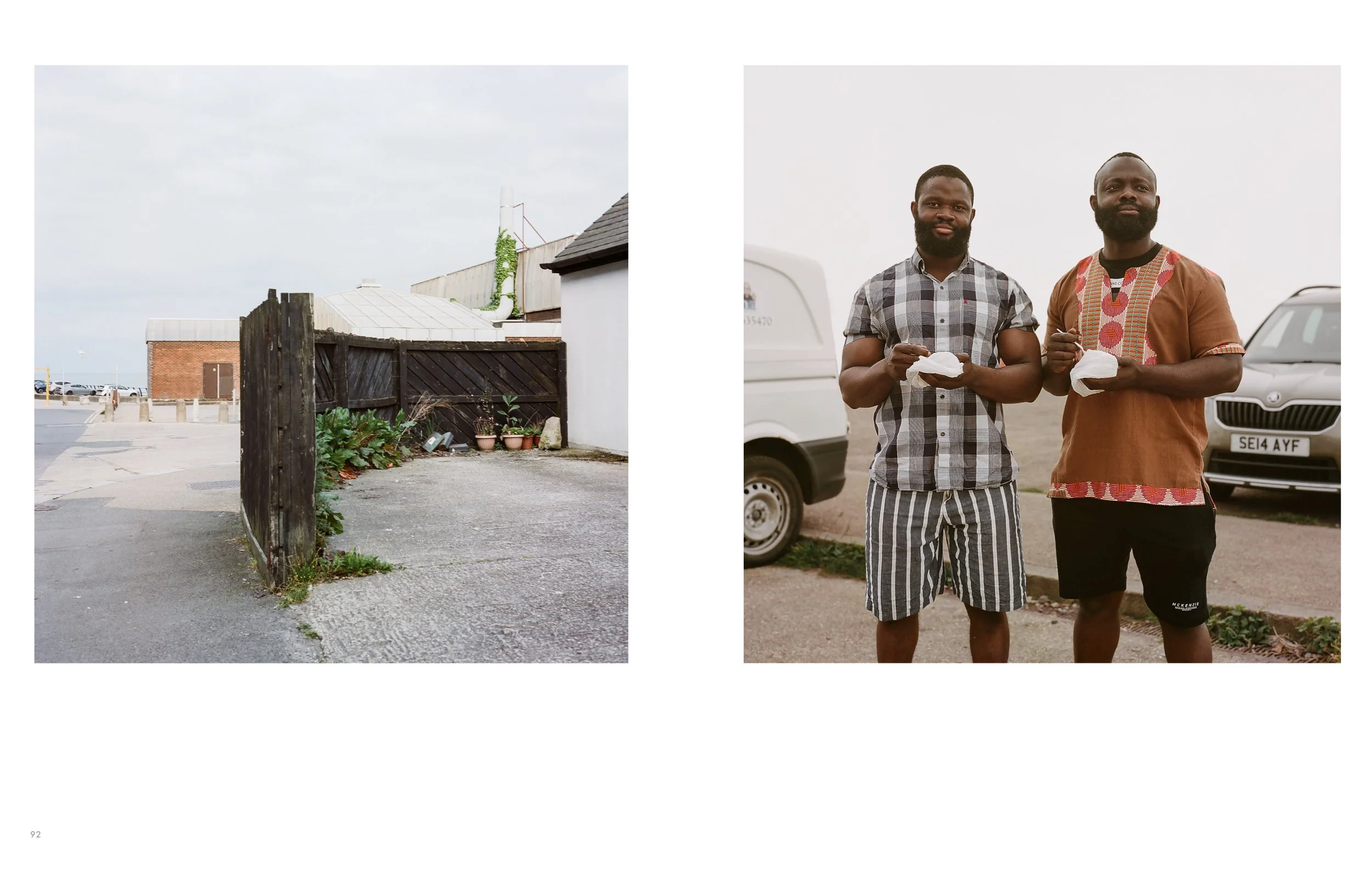 Two men standing outdoors near parked cars, holding food containers and eating, with a cloudy sky above.