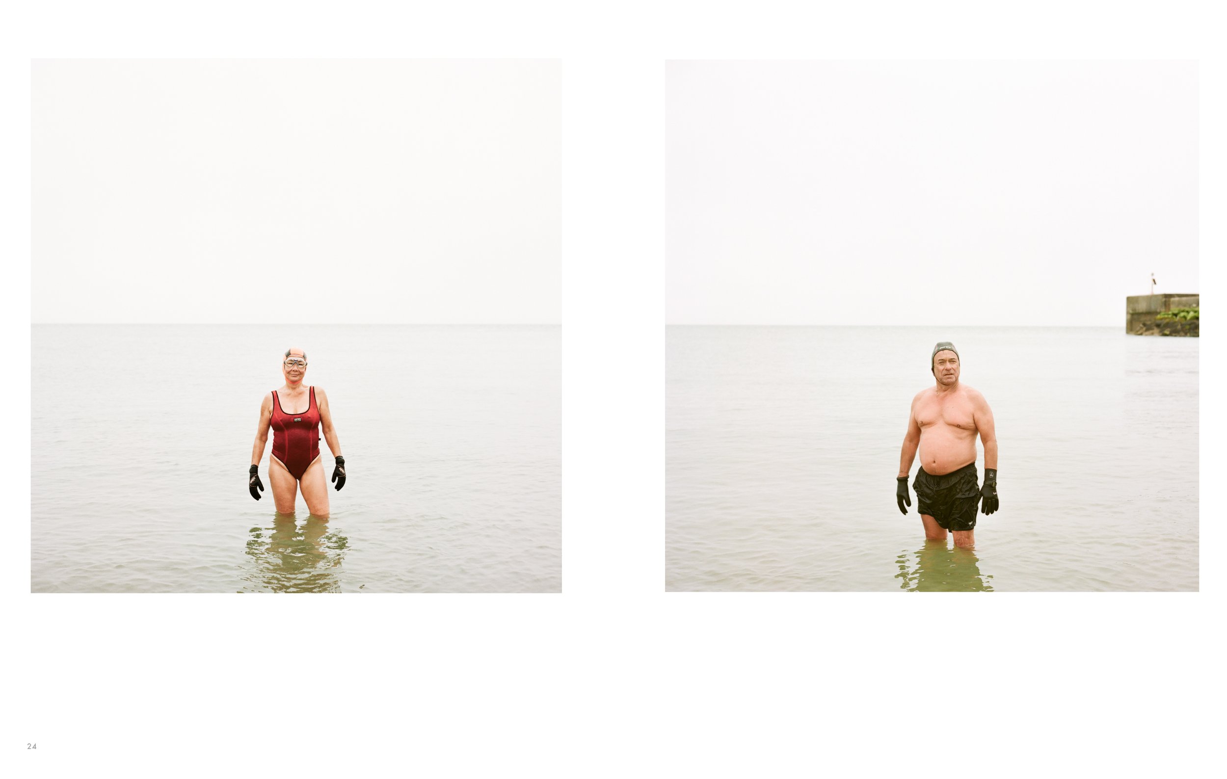 Two people standing in water at the beach; woman on the left wears a swimsuit and goggles, man on the right is shirtless and wearing shorts and a cap.