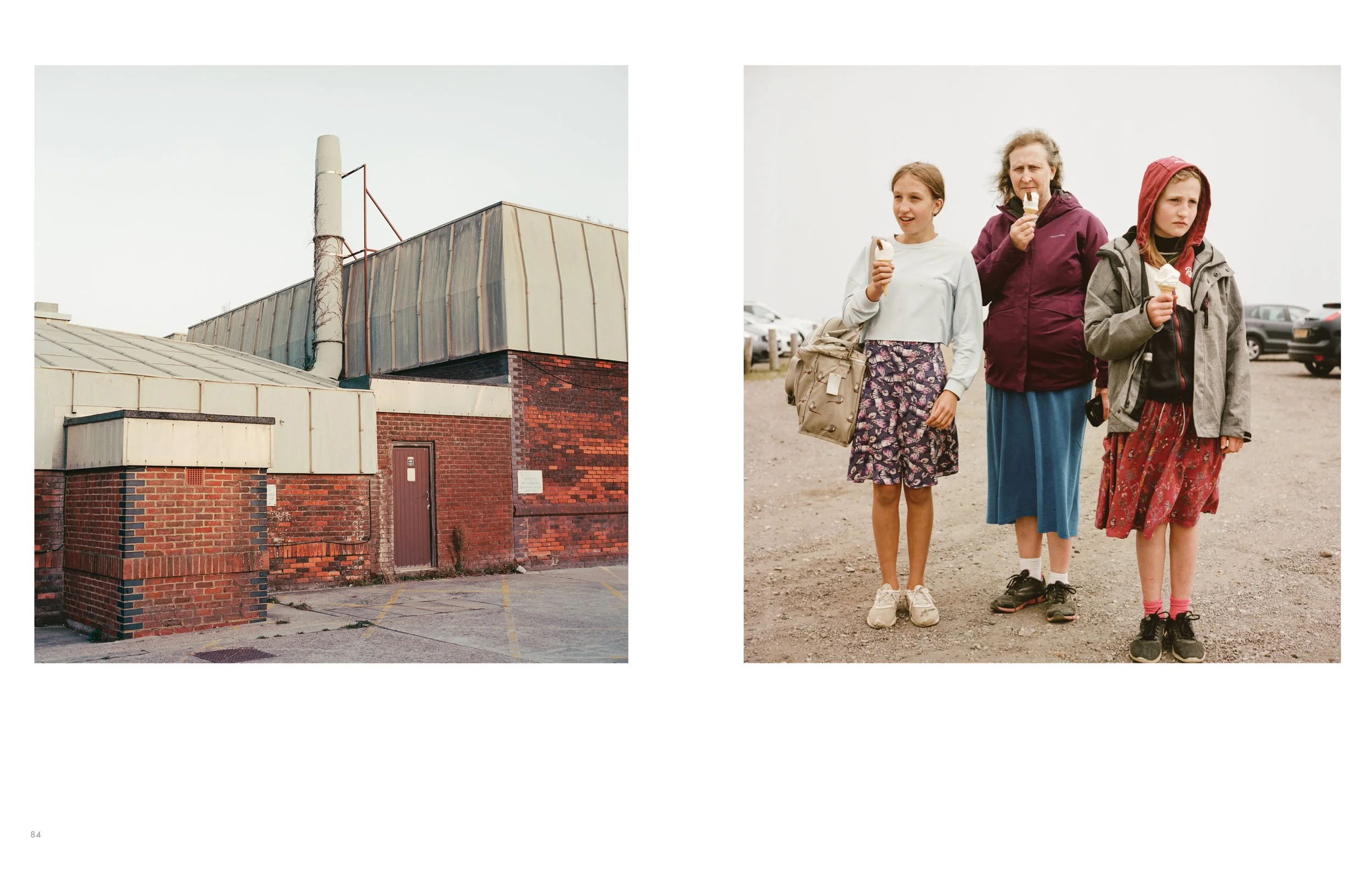 A building with a brick wall and a rusted metal roof on a cloudy day, and three women walking outdoors eating ice cream cones, dressed casually with jackets and skirts.