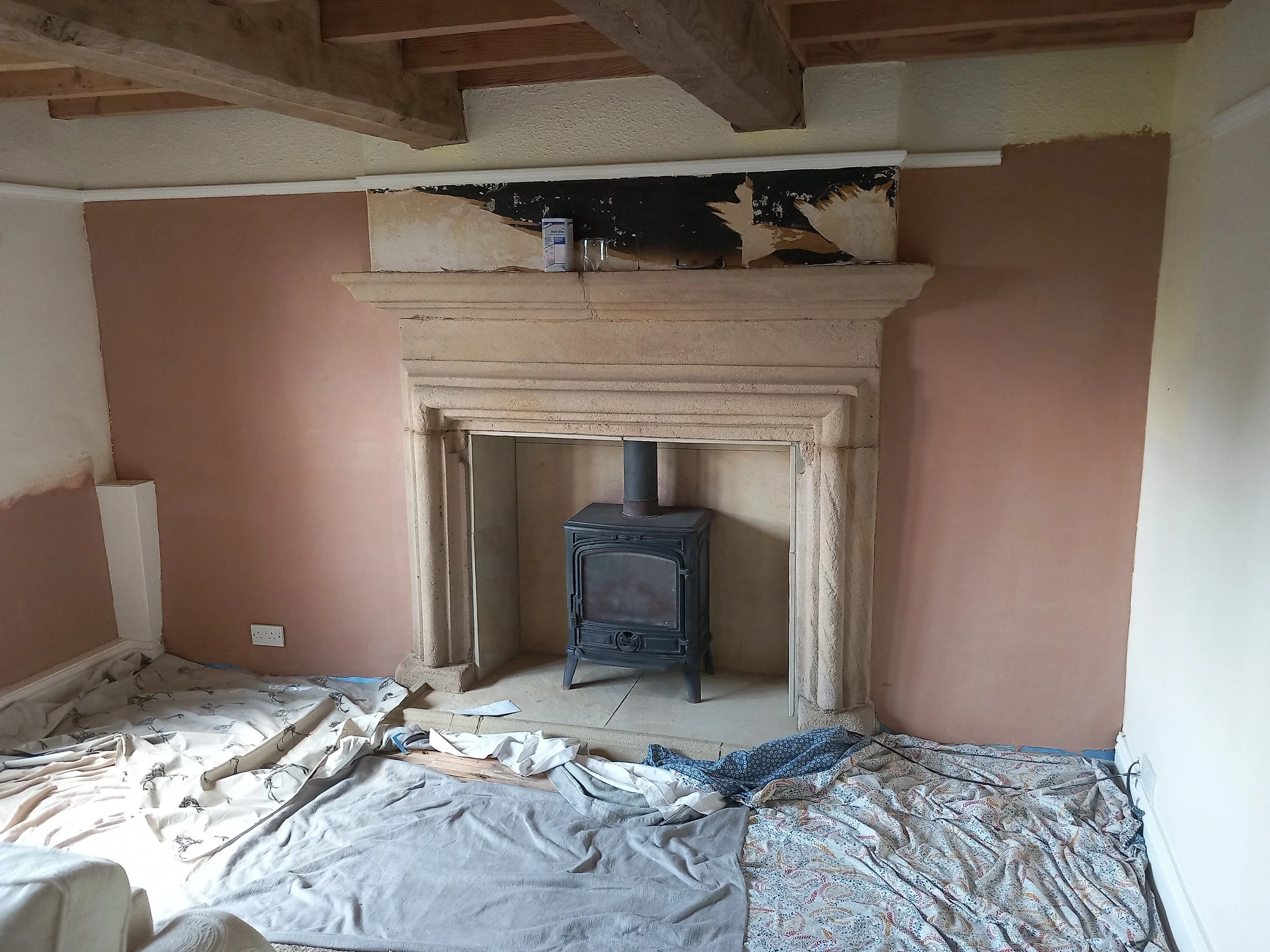 Living room with a fireplace, black stove, damp treatment finished and skimmed