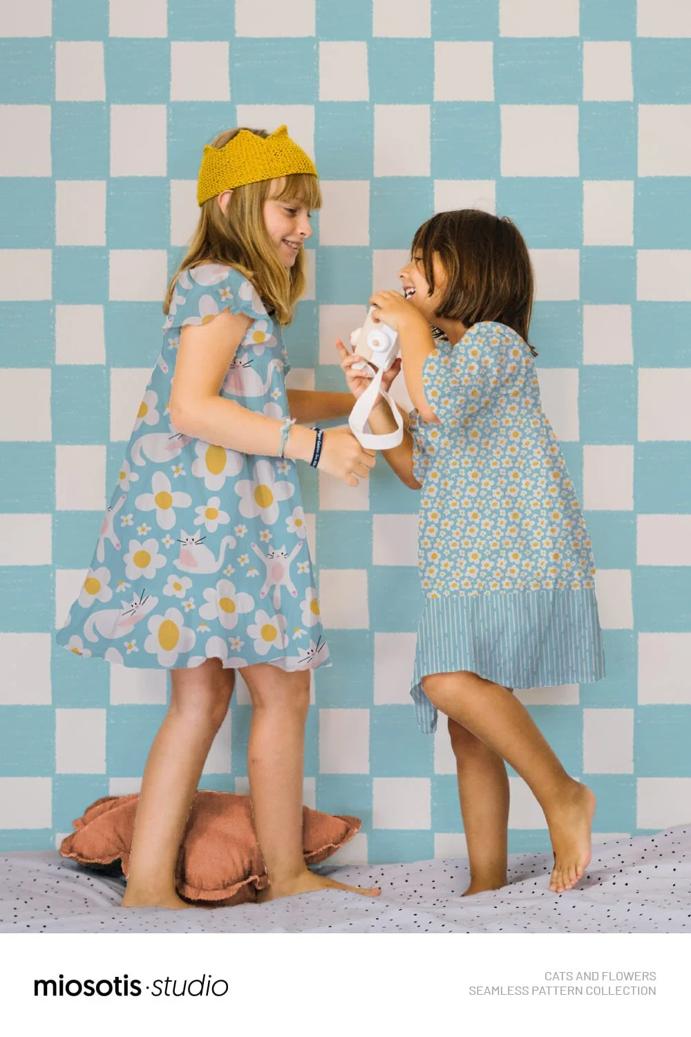 Two children wearing colourful dresses featuring the cats and flowers seamless pattern collection.
