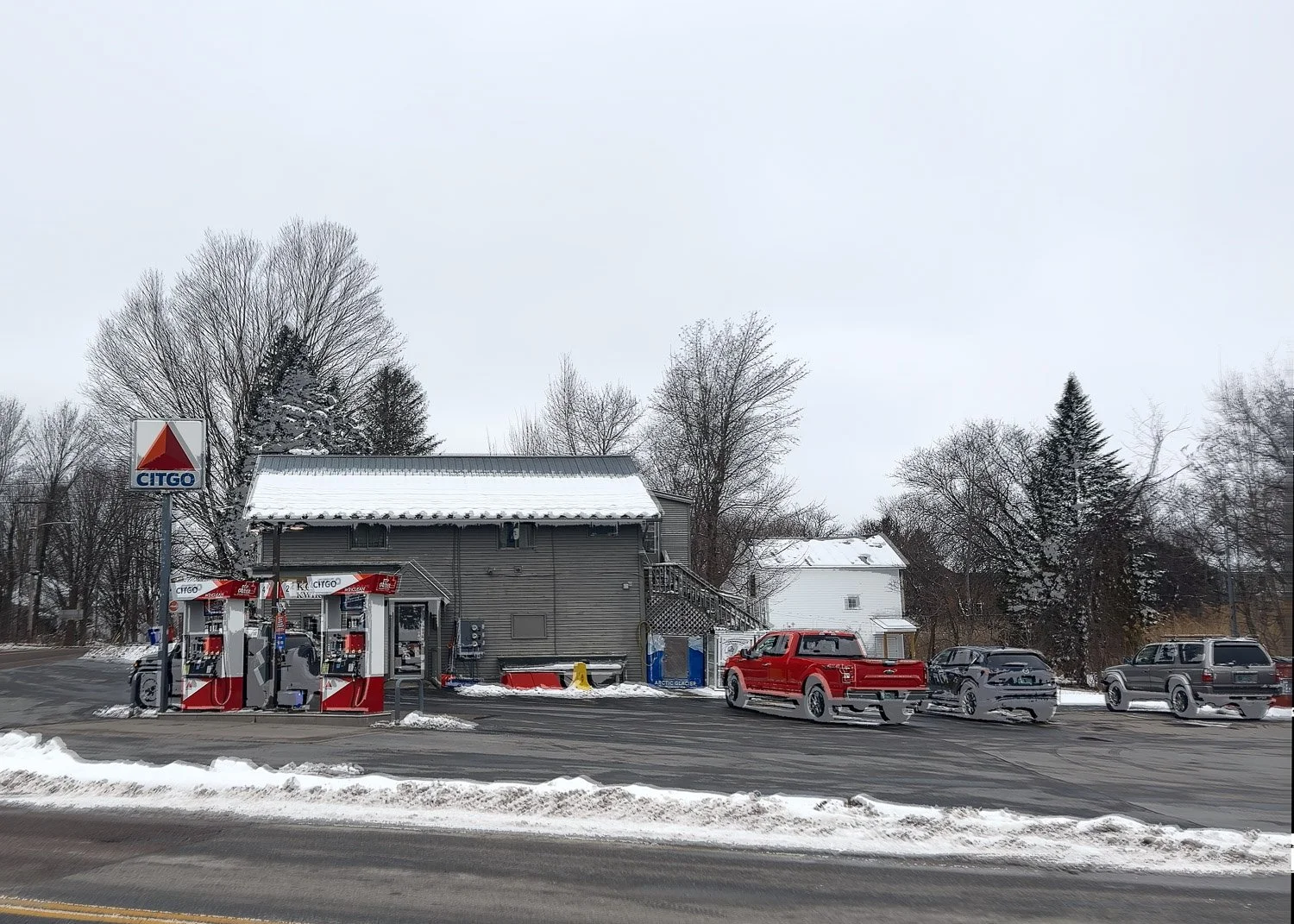 	
Abstract ICM Bluristic  photo - A CITGO gas station on a snowy day, with four gas pumps, several vehicles including a red pickup, parked in front, and leafless trees in the background.