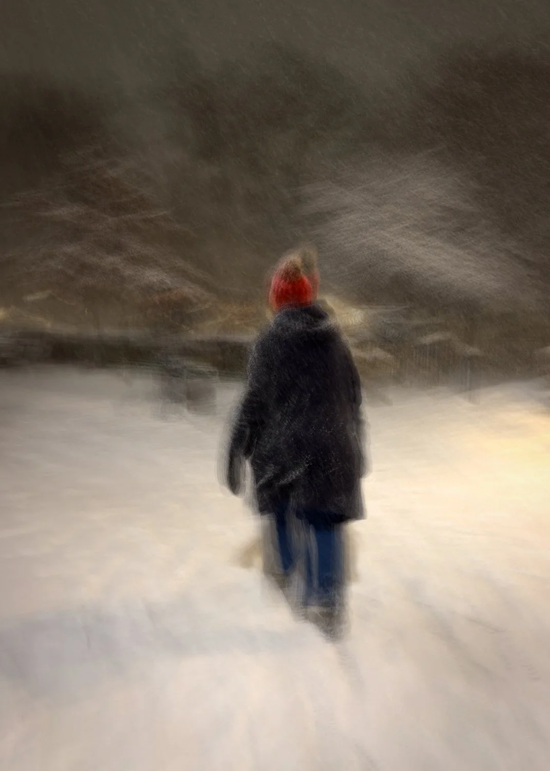 Abstract ICM Bluristic  photo - A person walking away in a snowy landscape during snowfall at night, wearing a dark coat and red hat.