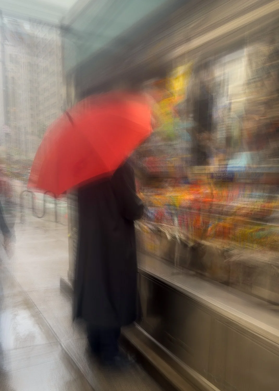 Abstract ICM Bluristic  photo - A person with a black coat and black pants holding a red umbrella, shopping for fruits or vegetables at an outdoor market on a rainy day.