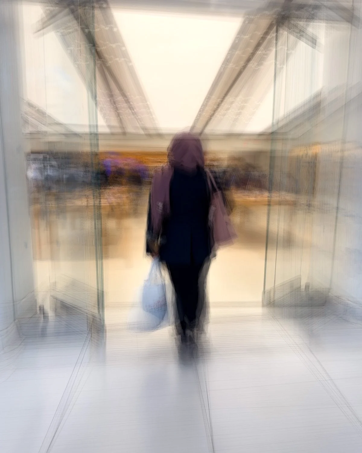 Abstract ICM Bluristic  photo - A person wearing a purple hoodie and black clothing walking through glass doors in an indoor setting, holding a grocery bag.