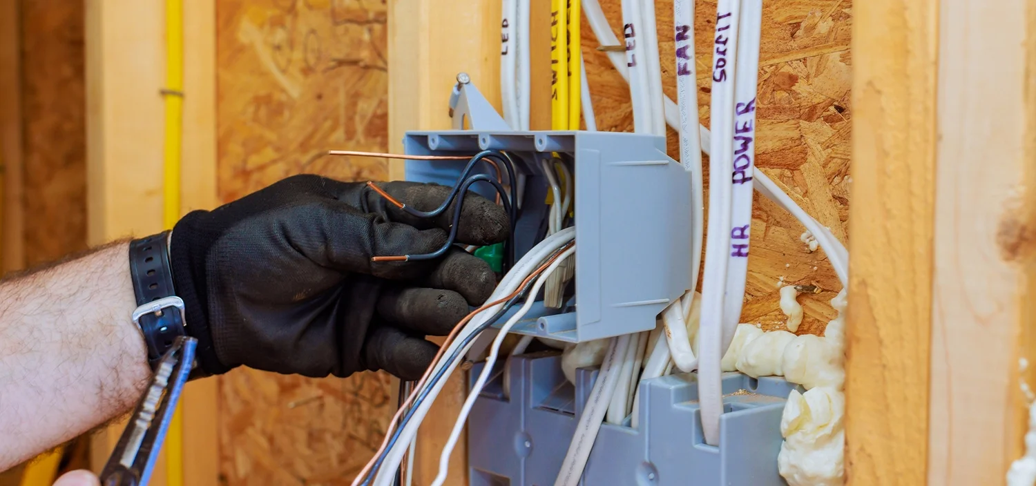 An electrician working with a mix of electrical wiring types, including Romex, THHN, and MC cable.