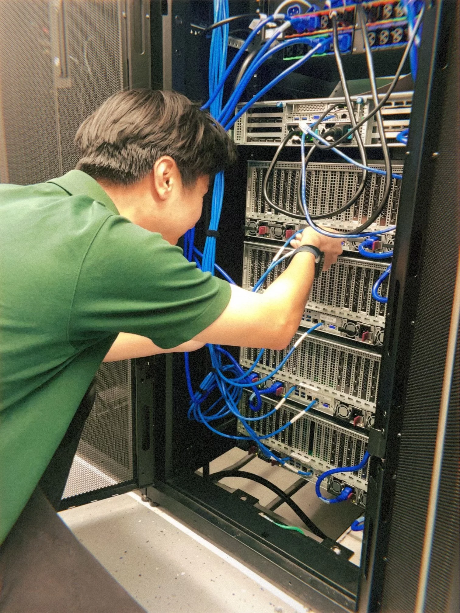 Technician wiring network cables into a server rack donated through Computing for Humanity.