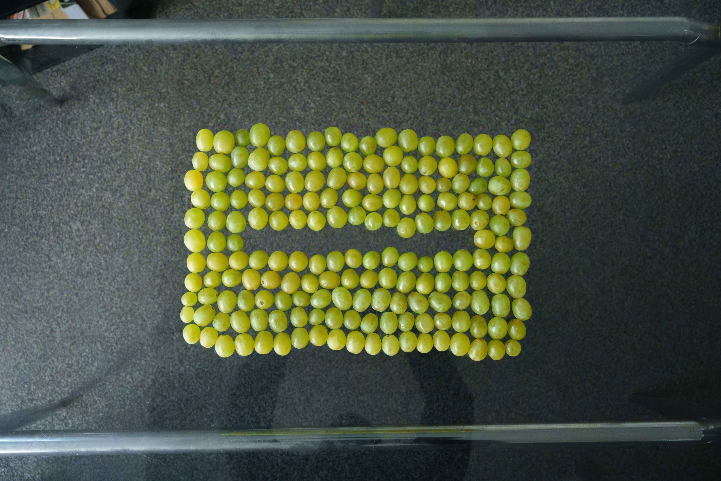 Green grapes arranged in a rectangular border on a dark gray textured surface.