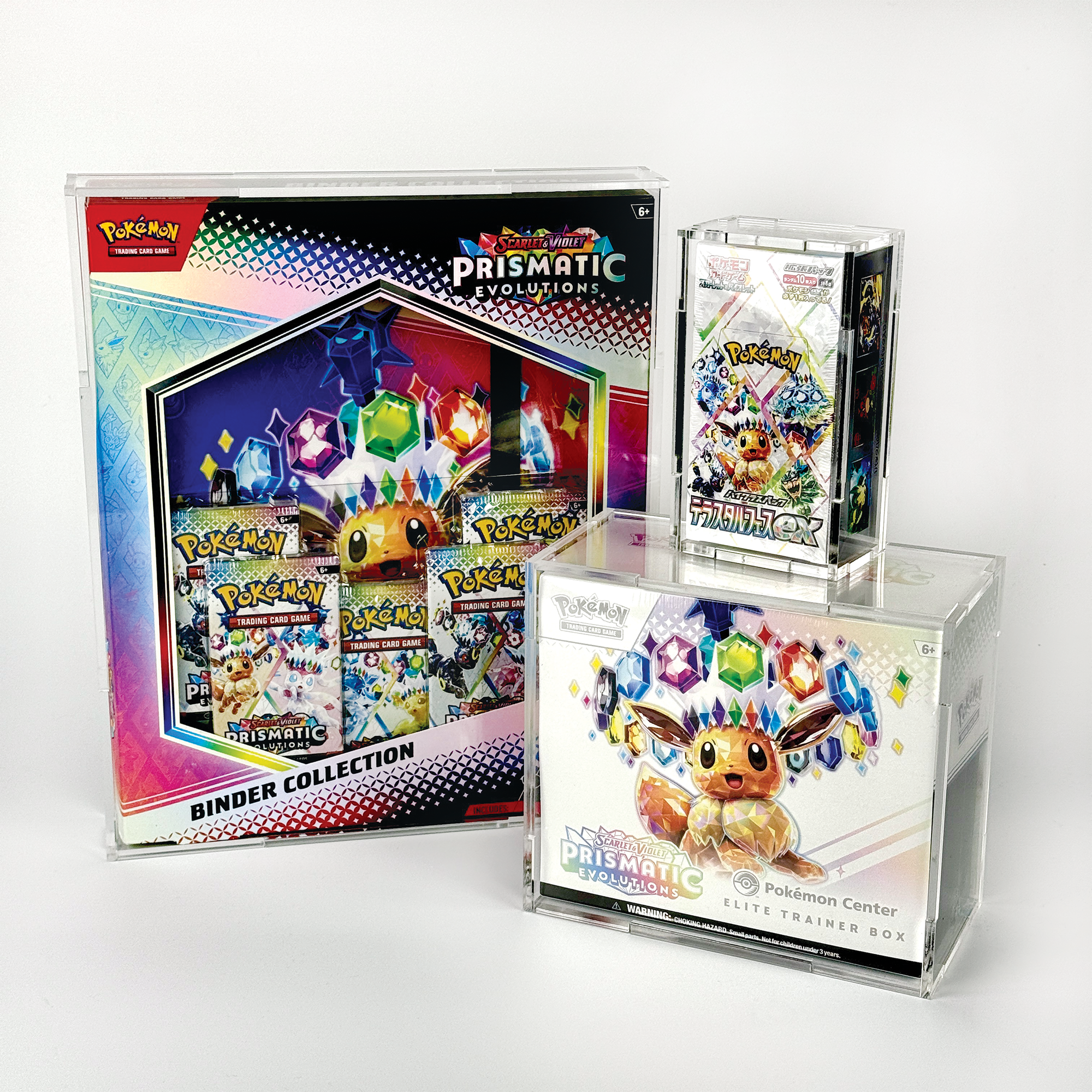 Display of Pokémon trading card game merchandise, including a large box set and individual booster packs, on a white background. Pokemon Prismatic Evolutions Set.