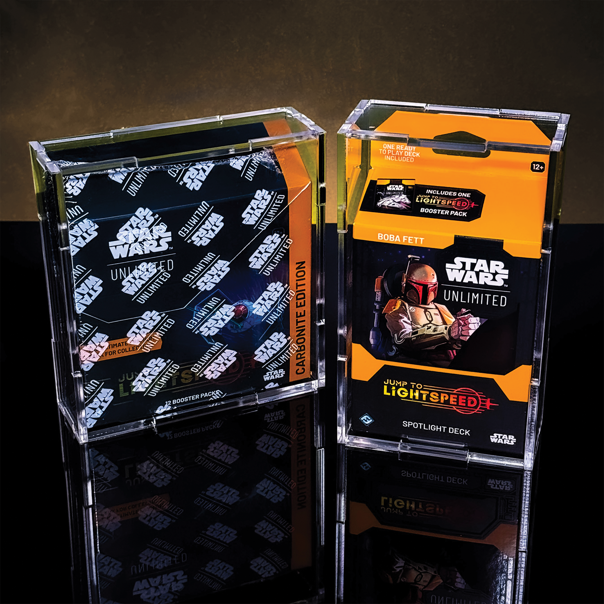 Two transparent acrylic display cases with Star Wars collectible card booster packs inside, placed against a dark background. The left case contains multiple packs with black and white branding, the right case has packs with yellow, black, and orange branding, including one labeled "Jump to Lightspeed Booster Pack."