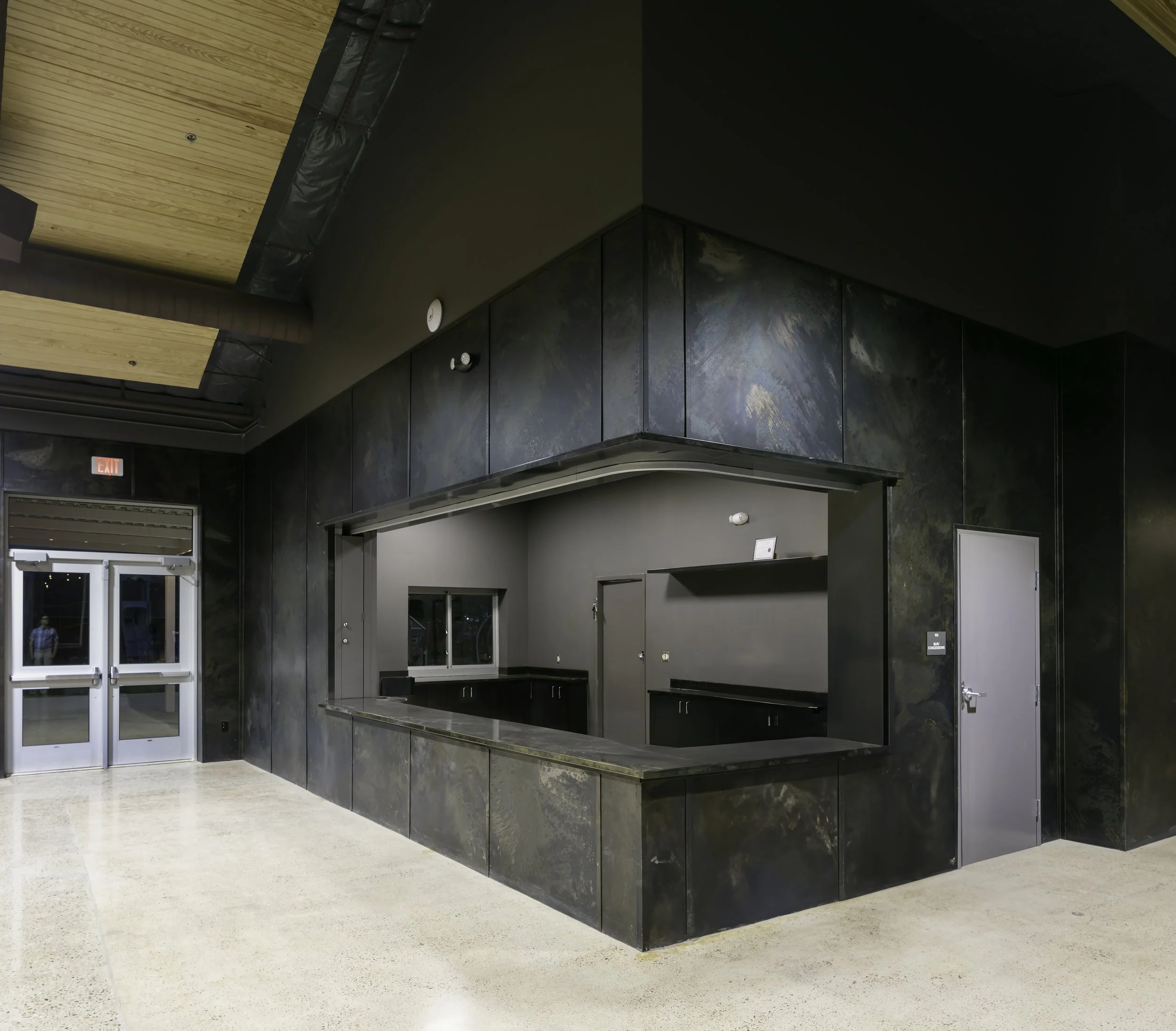 Renovated community bar outside of main event space with steel panel walls