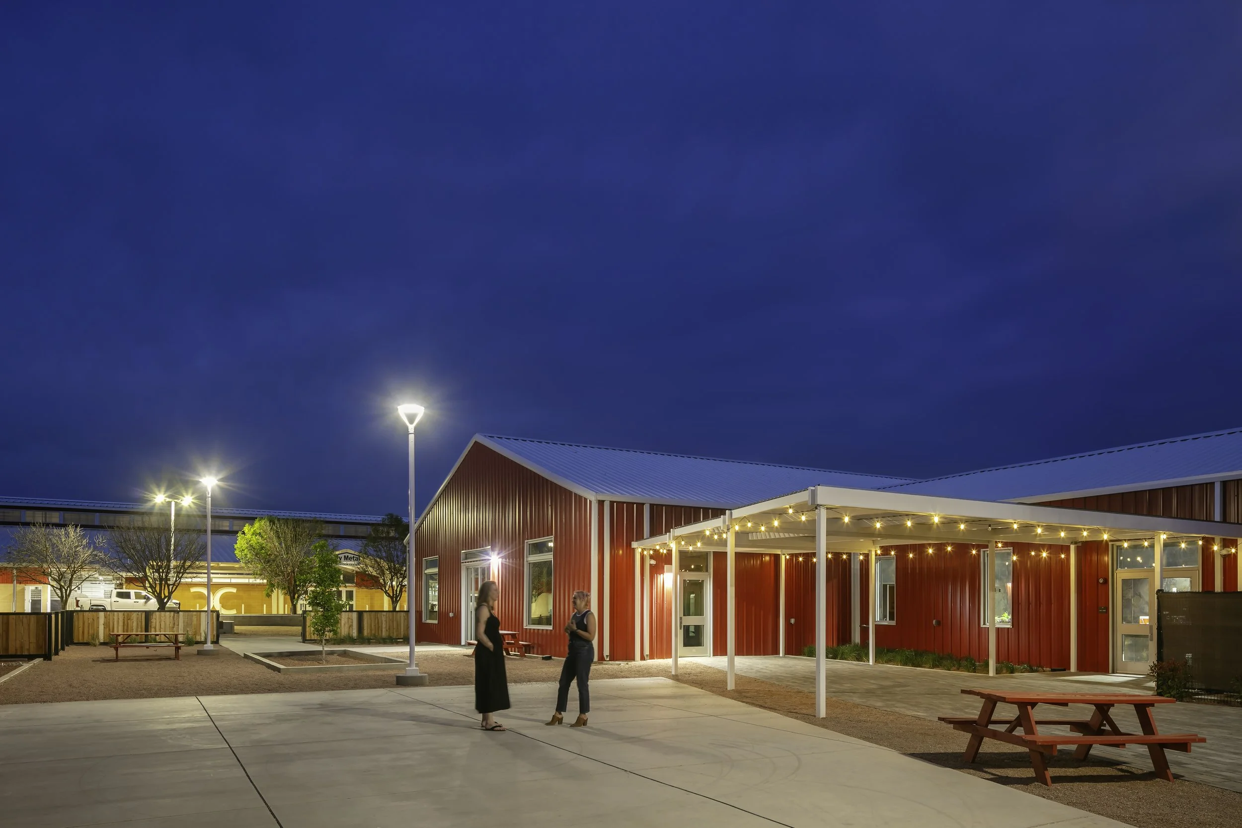 Renovated courtyard space with outdoor lighting and picnic tables adjacent to main event space