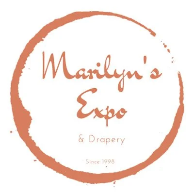 Logo for Marilyn's Expo & Drapery, established in 1998, featuring a circular brushstroke design.
