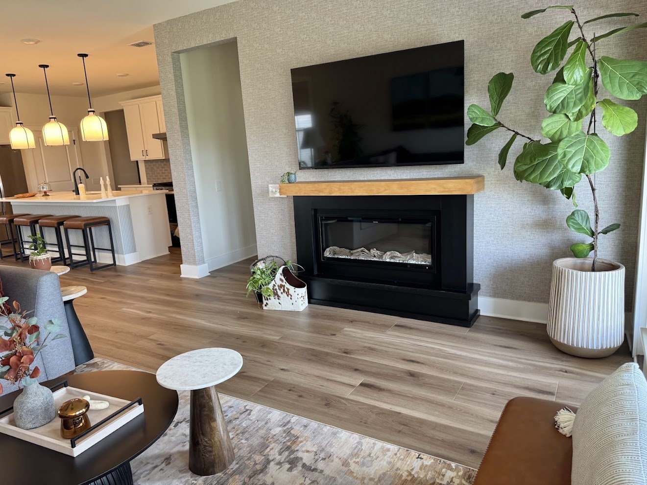 Modern transitional family room renovation that flows seamlessly into the adjacent kitchen, which also features black accents, leather, and wood elements.