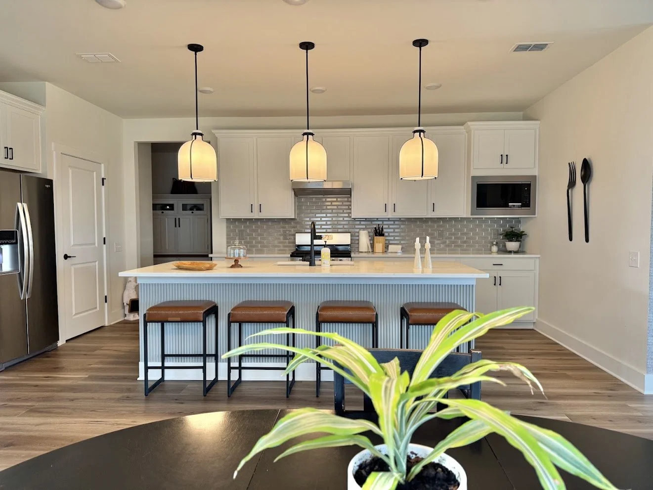 A fluted panel was added to the bottom of the island to add some eye-catchy element and some color while keeping the soft neutral palette. The leather counter stools bring warmth to the kitchen and grab the elements of the family room to create a bal