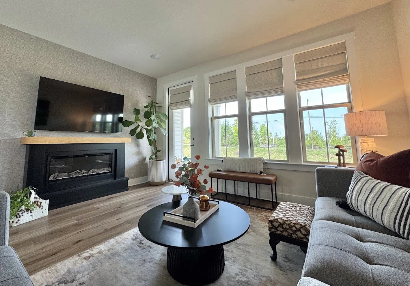 A modern transitional family room featuring contemporary black statement pieces, balanced by soft tans in the footstool and leather bench, and natural wood floor tones in this Hatfield, PA project.