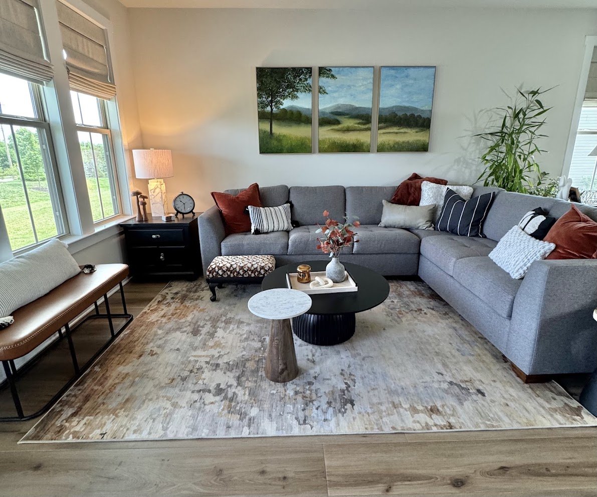 Modern transitional family room renovation in Hatfield, PA with warm, personalized elements. Clean lines meet plush comfort in a neutral palette of grays and creams, grounded by terracotta and deep brown, with layered textures that create a calming s