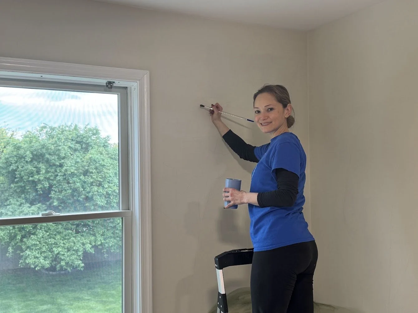 Designer Denisse Breaux hand-painting a custom forest mural, a personalized art detail that makes this guest room one of a kind.