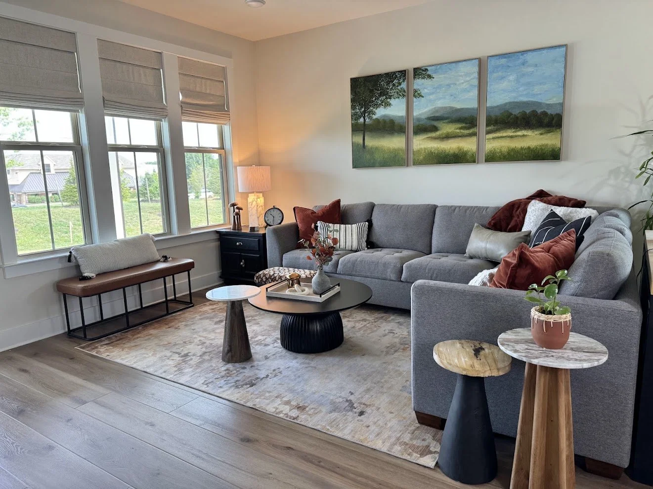 Modern Transitional Family Room with a neutral and warm palette. The room successfully mixes the sleek, clean lines of the round tables with natural wood and stone materials. They provide a variety of patterns to create interest.