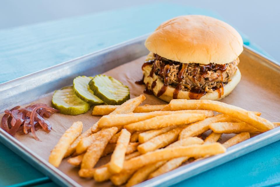 BBrad’s pulled pork sandwich with slow-smoked BBQ pork on a toasted bun, topped with pickles and house barbecue sauce, served with crispy golden French fries