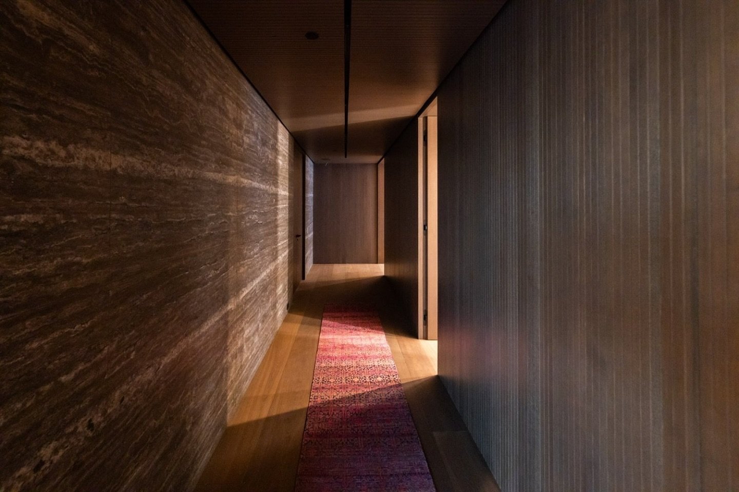 ✨ Simplicity Meets Sophistication ✨

This hallway is a masterclass in warm modernism, where materiality and lighting create an inviting yet dramatic atmosphere. The rich wood tones and natural stone walls establish a timeless palette, while the linea