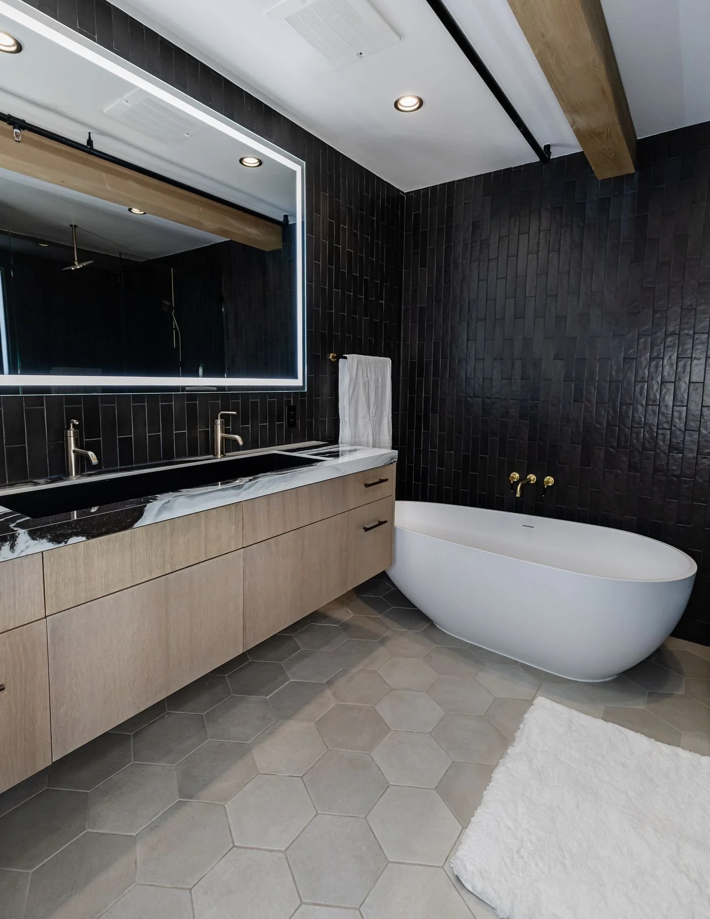 Designed with intention from the start.

The homeowner envisioned a dark, moody, Batman-inspired aesthetic throughout the space, creating the ultimate bachelor pad for time spent in town.

The bathrooms lean into that vision with rich tones, dramatic