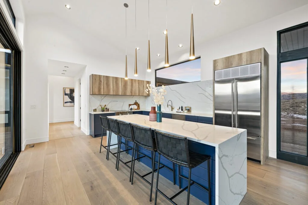 Icon-House-Benloch-Heber-City-Kitchen-Blue-Island-Quartz-Countertop-Brass-Pendants-Hallway-View-Roderick-Builders-Modern-Custom.jpg