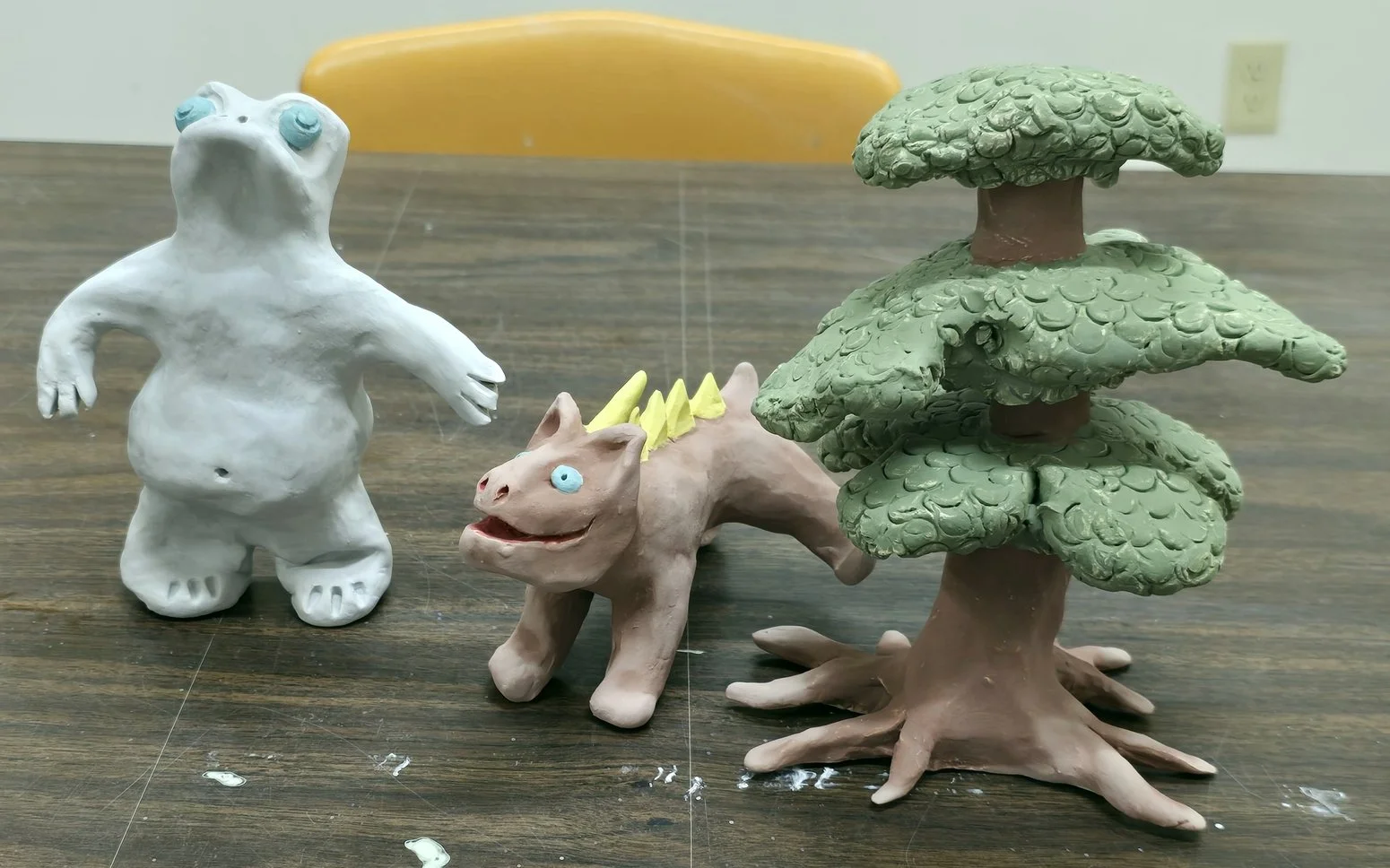 Three handmade clay figurines, in the style of Dr. Seuss, on a wooden table