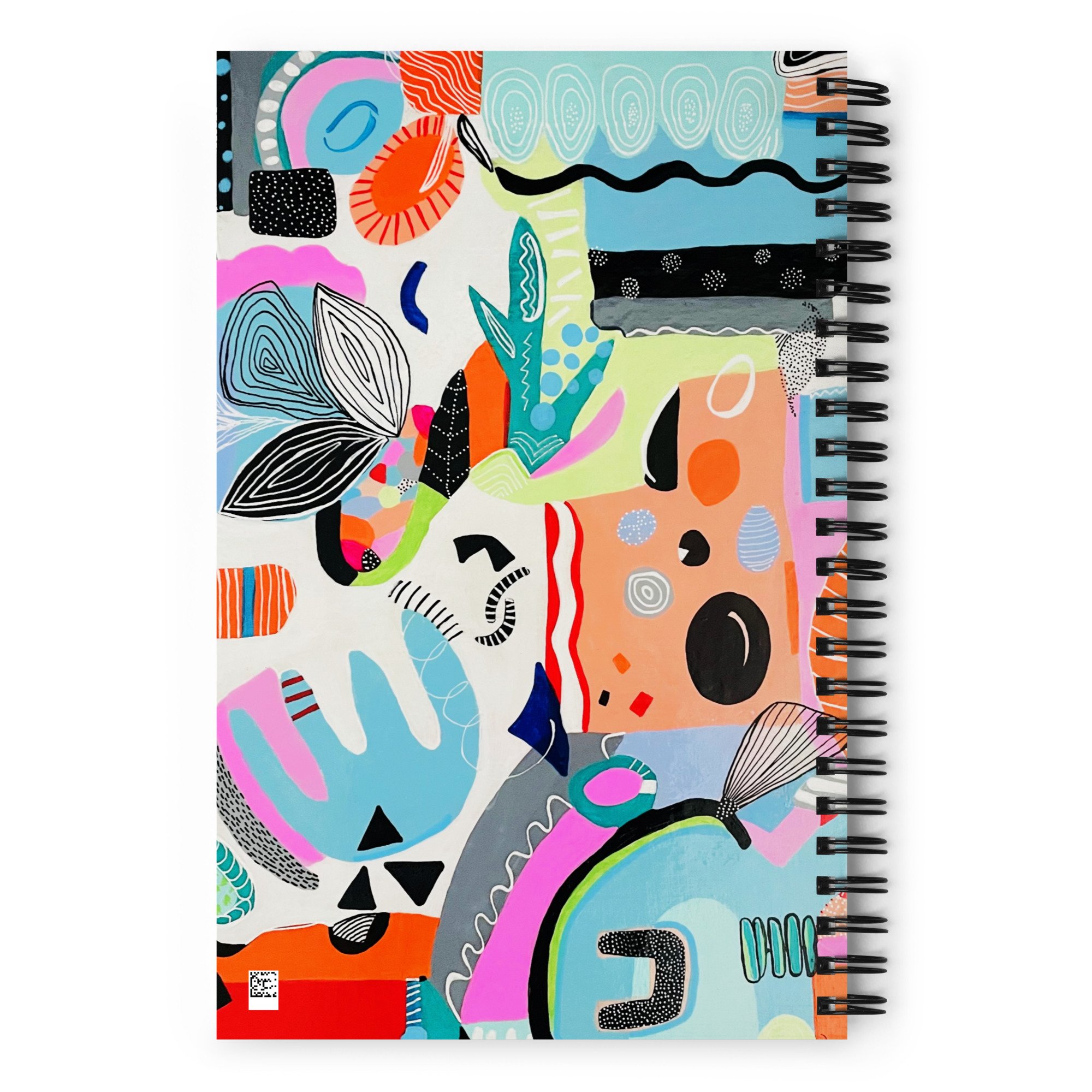 spiral notebook with colorful "synchronicity" art applied to the back cover