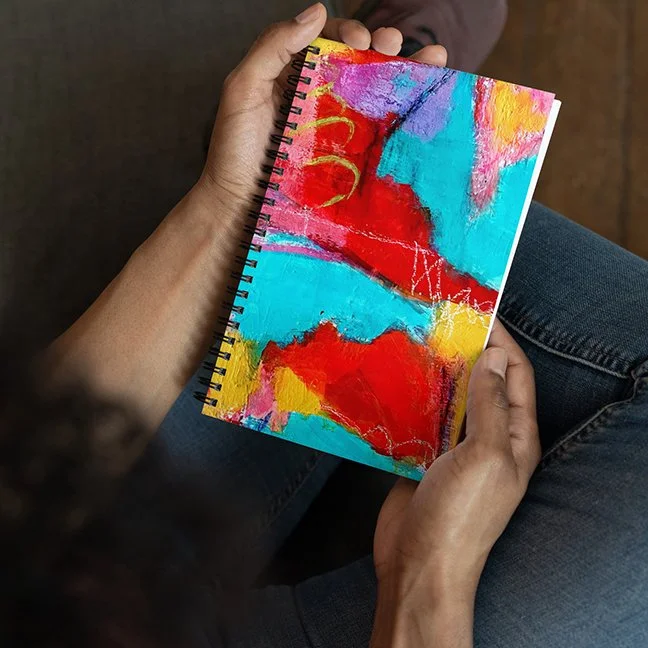 person holdig spiral notebook with colorful "Abstract #2" art applied