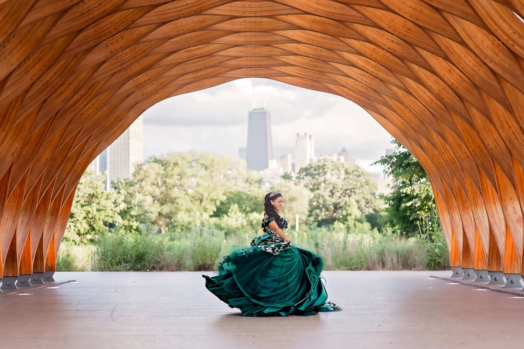 Quinceañera dancing during a fun photoshoot in a green ball gown at the honeycomb structure in Lincoln Park, Chicago.